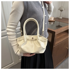 Detail of a creamy white pleated bucket bag with glossy finish and cylindrical handles