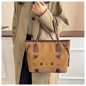 Detail of khaki suede tote bag with embroidered cat face and brown leather handle