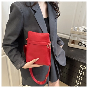 Close-up of red litchi texture leather crossbody bag with elegant gold metal hardware