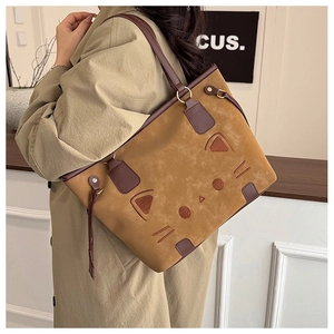 Detail of a large cat-themed tote bag in brown suede with decorative 3D ears and eyes