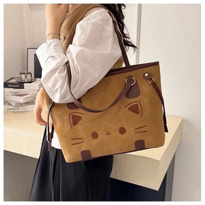 Detail of a large brown cat-themed tote bag with cat ears and embroidery worn by model