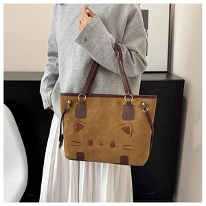 Detail of caramel brown tote bag with cat embroidery and golden hardware links