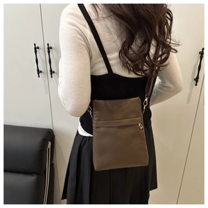 Rear view of a brown pebbled leather crossbody bag showing its size and wide strap style