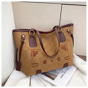 Detail of cute cat face embroidery on a large brown tote bag with gold metal hardware