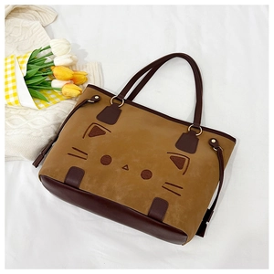 Detail of a brown cat-themed tote bag with cat face design and plush suede texture