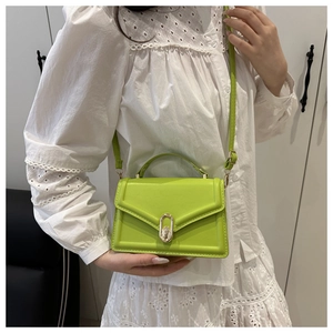 Detail of teal green PU leather bag featuring a gold oval twist lock and sleek top handle