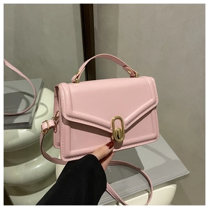 Detail van de zachtroze rechthoekige crossbodytas met gouden ovale sluiting en matte textuur