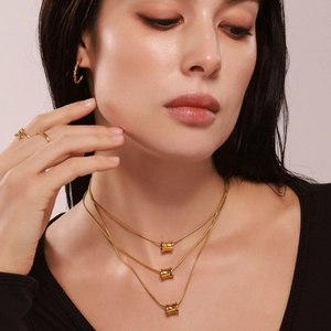 Gouden drielaagse ketting met cilindervormige hangers en bijpassende C-oorbellen
