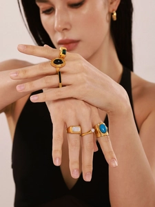 Close-up of vintage gold rings with emerald and turquoise stones on a model's hand