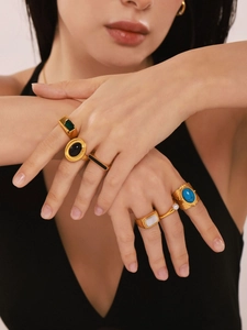 Close-up of vintage gold rings set with green, black and turquoise stones on a hand