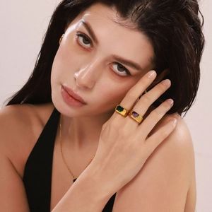 Detail shot of model wearing a gold jewelry set with emerald and amethyst rings