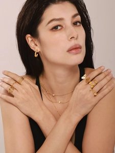 Close-up of model wearing gold irregular rings, star pendant necklace and C-shaped earrings