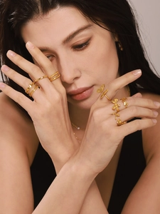Close-up of layered 18K gold plated rings with butterfly motifs and a pearl necklace