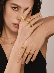 Close-up of irregular 18K gold-plated titanium rings and layered pearl necklace on model