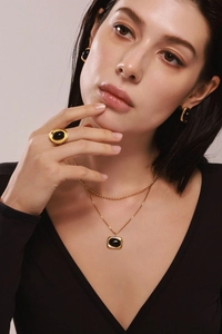 Nahaufnahme eines eleganten vergoldeten Schmucksets mit schwarzen Onyx-Anhängern an einem Model