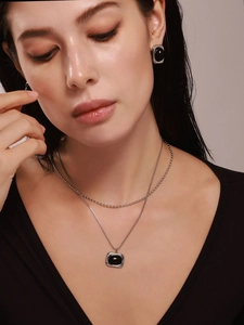 Details einer silbernen Layer-Halskette mit schwarzen Achat-Anhängern und passenden Ohrringen
