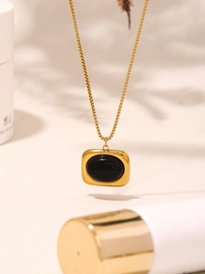 Detailansicht einer goldfarbenen Halskette mit einem schwarzen ovalen Edelsteinanhänger
