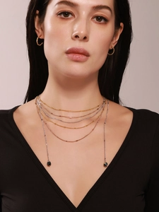 Close-up of layered tri-color metal chain necklace with natural dark gemstone pendants