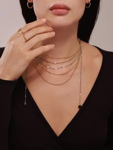 Close-up of layered 18k gold plated necklaces with natural stones on elegant model
