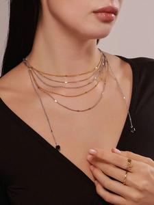 Close-up of layered mixed-tone chains with a delicate rose-shaped gold open ring