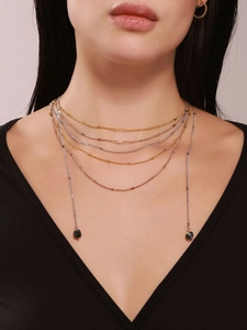 Detail of layered gold and silver chain necklace with black natural stone pendants