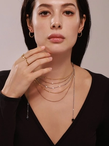 Detailed view of layered multi-strand gold and silver necklaces on model with tassel stone