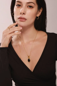 Détail du long collier plaqué or 18K avec pierre œil de tigre sur un haut noir en col V