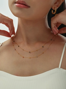 Detalle de un collar dorado de doble capa con cuentas de colores en una modelo