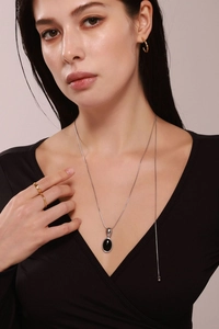 Détail du collier avec pendentif ovale en œil de tigre sur une longue chaîne dorée