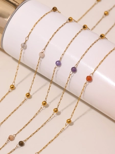 Detalle de cadena fina dorada con piedras naturales de colores y cuentas metálicas
