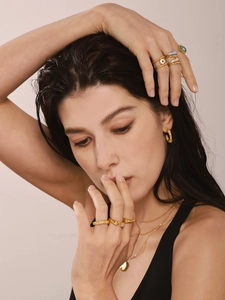 Close-up of gold rings with blue enamel evil eye charms and layered chain necklace set