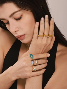 Detailed view of layered 18K gold plated evil eye enamel rings worn by a model