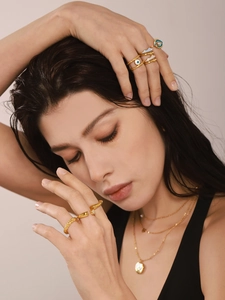 Detail of layered gold necklaces with evil eye enamel rings on model