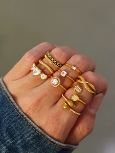 Detailed stacked view of diverse gold rings featuring zircon and emerald stones on hand