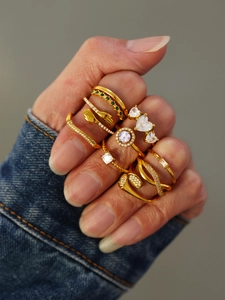 Close-up of stacked gold rings with green and white cubic zirconia on a model hand