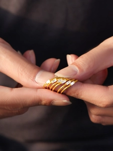 Close-up of stacked gold rings with rectangular 5A zircon stones shown on hand