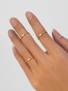 Close-up of three gold stacked rings with rectangular zircons on a model's hand