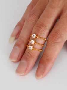 Κοντινό πλάνο τριών πλεχτών δαχτυλιδιών 18K χρυσού με τετράγωνες πέτρες ζιργκόν