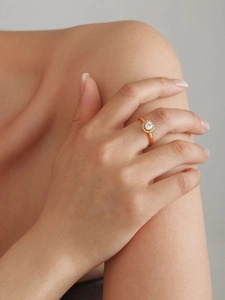 Detailed view of a gold titanium ring with a halo of sparkling cubic zirconia on a finger