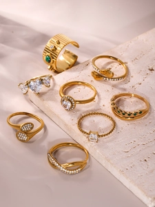 Detailed view of eight gold plated rings with colorful zircon on a textured stone base