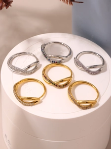 Detailed view of geometric crisscross rings with colorful cubic zirconia on white stands