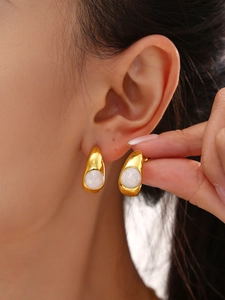 Vue détaillée de boucles d'oreilles en forme de C dorées avec incrustation en résine blanche