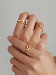 Détail de trois bagues câlin dorées avec zircons portées aux doigts d'un mannequin