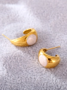 Gros plan de boucles d'oreilles dorées en forme de C avec nacre sur fond de fausse fourrure