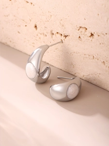 Vue macro de boucles d'oreilles argentées en C avec incrustation ronde en résine blanche
