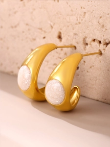 Vue macro de boucles d'oreilles C dorées à l'or 18 carats avec cristal blanc scintillant