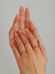 Detail of three gold layered rings with green zircon stones worn on a hand