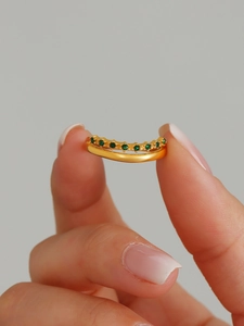 Close-up of 18k gold plated ring featuring a wavy design set with green zircons