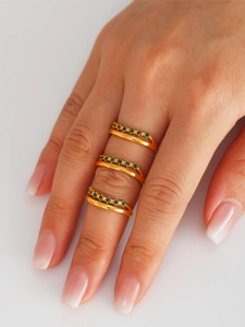 Macro shot of gold plated stackable rings with green zircon stones on fingers