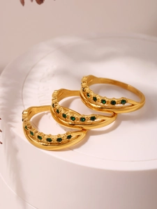 Macro detail of three 18k gold plated wavy rings with emerald green zircon stones